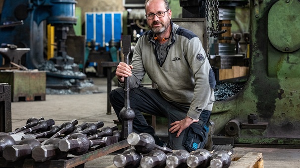 Martin Wensauer vom Rottaler Hammerwerk mit verschiedenen Glockenklöppeln. Er ist der Geschäftsführer des Familienunternehmens. | Bild: picture alliance/dpa | Armin Weigel