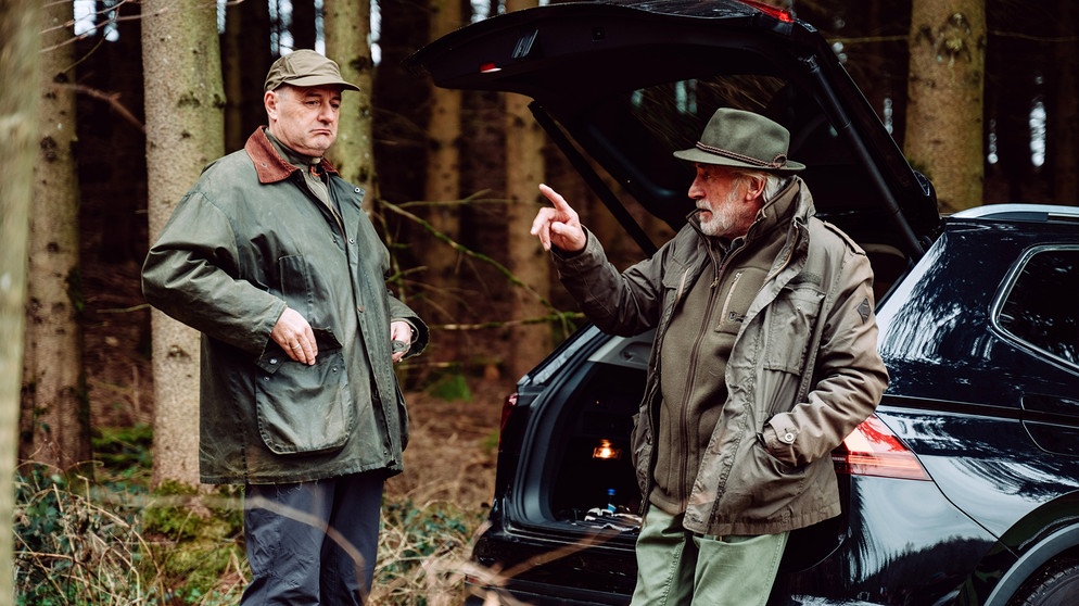 Dahoam is Dahoam: Hubert (Bernhard Ulrich, links) kann nicht nachvollziehen, warum Martin (Hermann Giefer) so wütend ist, als er sich ungefragt dessen Gewehr nimmt. | Bildquelle: BR/Nadya Jakobs