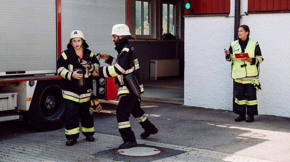 Dahoam is Dahoam: Beim Probealarm merkt Naveen (Markus Subramaniam), dass Tina (Anita Eichhorn, links) sich ihm gegenüber noch sehr verhalten zeigt. Mit Annalena (Heidrun Gärtner, rechts). | Bildquelle: BR/Nadya Jakobs