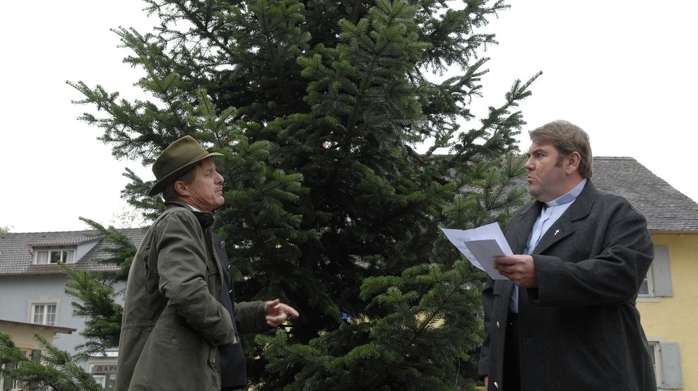 Pfarrer Neuner und Bürgermeister Schattenhofer finden einen Erpresserbrief in den Zweigen der Lansinger Weihnachtstanne. Von links: Bürgermeister Schattenhofer (Werner Rom) und Pfarrer Neuner (Peter Rappenglück). | Bildquelle: BR/Marco Orlando Pichler