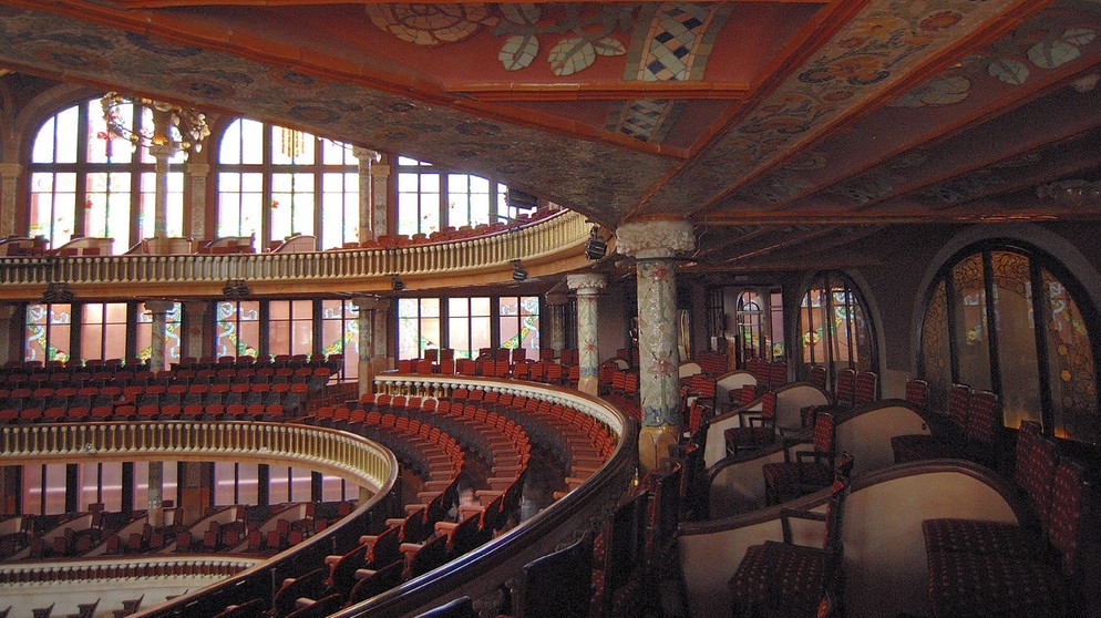 Palast der katalanischen Musik Barcelona/Palau de la Música Catalana, Barcelona: Der große Konzertsaal ist das Herzstück des Konzerthauses. Wandmalereien, Glas- und Keramikelemente machen den Saal zu einem opulenten ästhetischen Erlebnis. Die Akustik des Saales wurde ursprünglich für Chormusik angelegt. Der Musikpalast wurde von 1905 bis 1908 erbaut. | Bildquelle: SWR/Alfons Früh