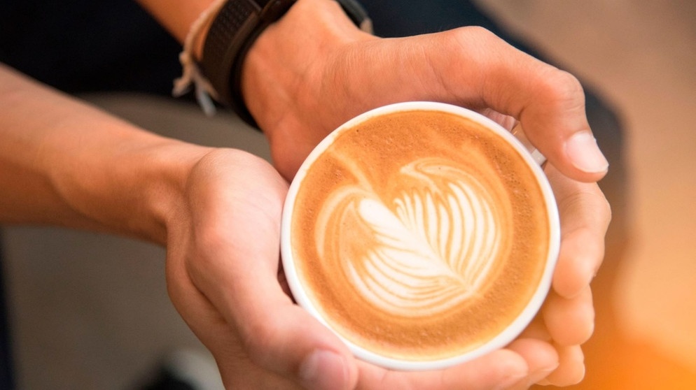 Mann hält Tasse mit Capuccino mit Hafermilch | Bildquelle: mauritius images