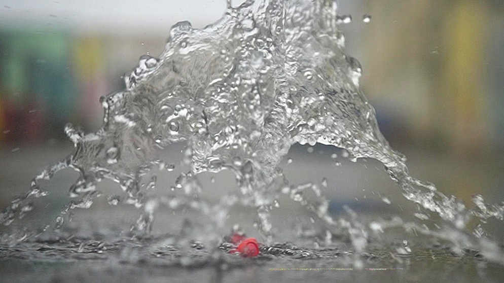 Momentaufnahme eines Wasserstrahls, der auf eine Rose herabfällt. | Bildquelle: BR