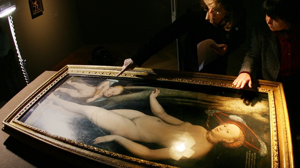 Expertinnen untersuchen das Bild "Venus und Amor als Honigdieb" von Lucas Cranach dem Älteren. | Bildquelle: picture-alliance/dpa/Boris Roessler