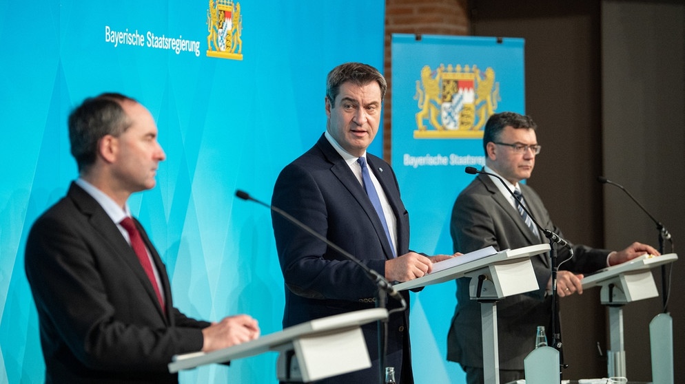 06.12.2020, Bayern, München: Markus Söder (CSU, M), Parteivorsitzender und Ministerpräsident von Bayern, spricht nach einer Kabinettssitzung zur weiteren Entwicklung in der Corona-Pandemie auf einer Pressekonferenz. Neben ihm stehen Hubert Aiwanger, Wirtschaftsminister und Landesvorsitzender der Freien Wähler in Bayern (l), und Florian Herrmann (CSU), Leiter der bayerischen Staatskanzlei. Das Kabinett hat zuvor per Video-Schalte getagt. Foto: Matthias Balk/dpa +++ dpa-Bildfunk +++ | Bildquelle: dpa-Bildfunk/Matthias Balk